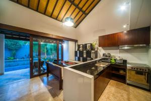 a large kitchen with a counter and a large window at Tirta Villa in Sanur