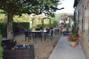 patio con tavolo e sedie sotto un albero di Domaine Lacoste a Carsac-Aillac