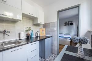 a kitchen with white cabinets and a sink at Noctis Apartment Powiśle in Warsaw