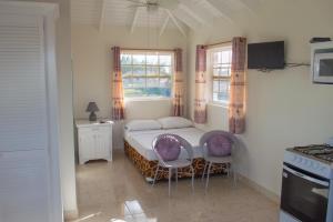 a small bedroom with a bed and two chairs at Plover Court Apartments in Christ Church