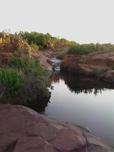 un río con rocas y árboles en el fondo en Bateleur Nature Reserve, en Modimolle