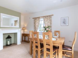 een eetkamer met een tafel en stoelen en een open haard bij Meadow View in Cirencester