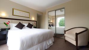 sypialnia z dużym białym łóżkiem i krzesłem w obiekcie Roosevelt Hotel & Suites w mieście Lima