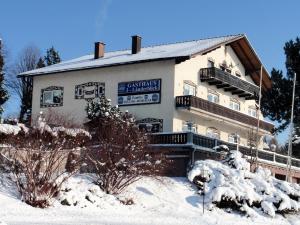 a building with snow on the ground in front of it at Gasthaus 3-Länderblick Mönichkirchen in Mönichkirchen