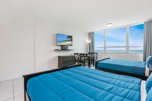 a hotel room with a blue bed and a table at Miami Beach Apartments by MiaRentals in Miami Beach