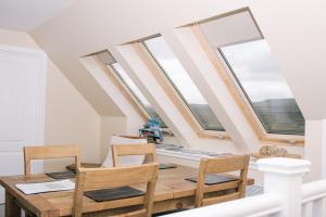 a dining room with a table and chairs and windows at Sea Shimmer in Portree