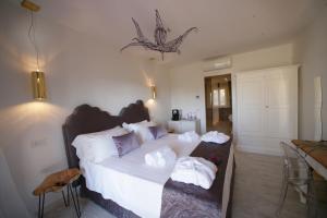 una camera da letto con un grande letto con lenzuola e cuscini bianchi di Geco di Giada Art Suites - Adult Only a Porto Rotondo