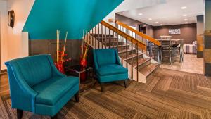 un vestíbulo con 2 sillas y una escalera en SureStay Plus Hotel by Best Western Post Falls, en Post Falls