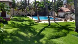 une cour avec une piscine bordée de palmiers et une cour dans l'établissement Pousada Via Lactea, à Canoa Quebrada