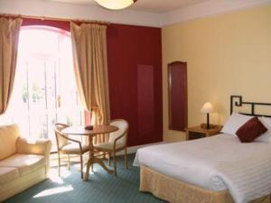 a hotel room with a bed and a table and chair at Woodlands Hotel & Leisure Centre in Waterford