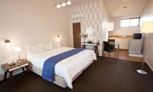 a bedroom with a large white bed and a kitchen at Broadway Motel & Miro Court Villas in Matamata