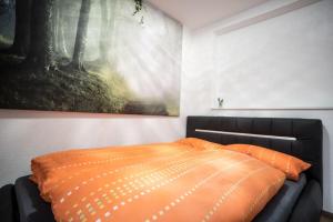 Ferienwohnung Hilber في Schmirn: سرير مع لحاف برتقالي في غرفة النوم