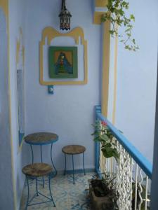 a staircase with two stools and a picture on the wall at Hôtel Dar Terrae in Chefchaouen
