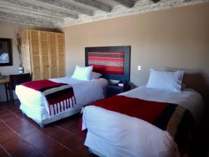 two beds in a hotel room with white and red sheets at Noi BordeLoa in Calama