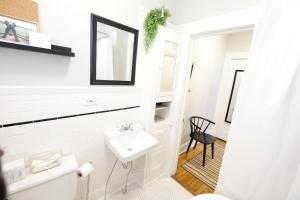 een witte badkamer met een wastafel en een spiegel bij 1920s CITY RETREAT Studio Flat in Dallas