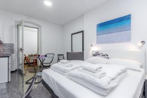 ein weißes Schlafzimmer mit einem großen Bett mit weißer Bettwäsche in der Unterkunft Apartments Black & White, Cherry & Blue in Rijeka