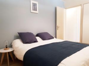 a bedroom with a large white bed with purple pillows at Appartement 60m2 / Hyper Centre (Gares et Vieux Lille) in Lille