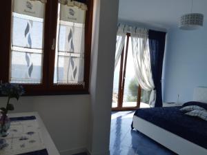 a bedroom with a bed and two windows with curtains at Casa Notaro Sorrentino in Acciaroli