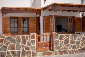 a house with wooden doors and a stone wall at Ayfa Apartment in Punta Mujeres
