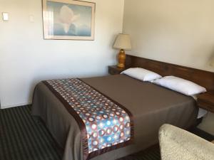 a hotel room with a bed and a chair at Sunrise Motel in Sparks