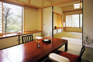 a dining room with a wooden table and a large window at Oyado Uraku in Yufu