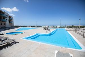 a large swimming pool with blue water in a resort at Ericeira Lounge Seaside Apartment in Ericeira