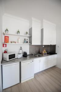 a white kitchen with white cabinets and a microwave at Ericeira Lounge Seaside Apartment in Ericeira