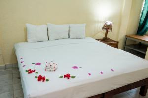 Un dormitorio con una cama blanca con flores. en Villa Diamante en Zihuatanejo