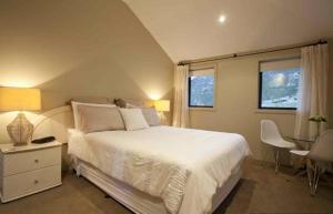 a bedroom with a white bed and a table and chairs at Gibbston House Boutique B&B in Gibbston +25 photos