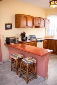 a kitchen with a counter with a microwave and two stools at Villa Diamante in Zihuatanejo