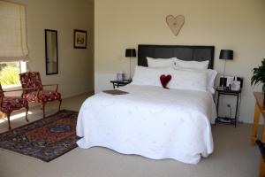 a bedroom with a white bed with a red heart on it at L'abri Bed and Breakfast in Akaroa