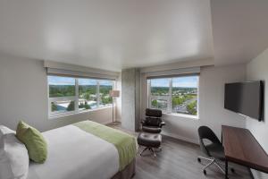 a hotel room with a bed and a desk and two windows at Hotel Interurban in Tukwila
