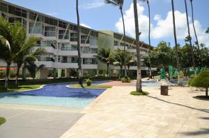 ein Resortgebäude mit einem Pool und Palmen in der Unterkunft Ancorar Flat 4203 in Porto De Galinhas