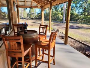 a porch with chairs and a table with a barrel at Woodlane Cottages Hunter Valley in Lovedale