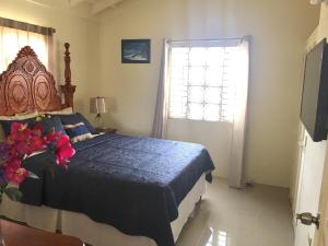 a bedroom with a bed with a blue comforter and a window at Drax Hall Country Club's Sweet Escape in Saint Annʼs Bay