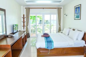 Schlafzimmer mit einem Bett, einem Schreibtisch und einem TV in der Unterkunft Ananda Villa - SHA Plus in Ko Tao
