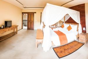 a bedroom in a villa with a bed and a television at The Kalangan in Ubud
