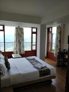 a bedroom with a large bed with windows and a desk at Hotel Ninamma in Gangtok