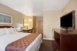 Travelodge by Wyndham Everett City Center في إيفريت: غرفة فندقية بسرير وتلفزيون بشاشة مسطحة