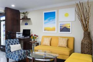 Days Inn by Wyndham Goose Creek في تشارلستون: غرفة معيشة مع أريكة صفراء وطاولة زجاجية
