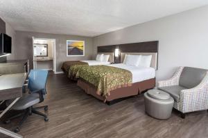 a hotel room with two beds and a desk and chairs at Days Inn by Wyndham Goose Creek in Charleston
