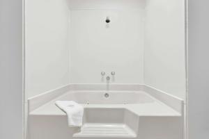 a white bath tub in a white bathroom with a towel at Super 8 by Wyndham Rock Port MO in Rock Port