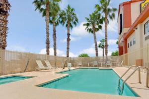 una piscina con palmeras y un edificio en Super 8 by Wyndham Tucson/Grant Road Area AZ en Tucson