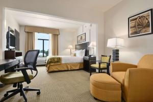 a hotel room with a bed and a desk and chairs at Wingate By Wyndham Frisco in Frisco