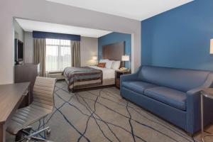 a hotel room with a bed and a couch at Wingate by Wyndham Indianapolis Airport Plainfield in Plainfield