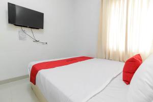a bedroom with a bed with a television on the wall at RedDoorz near Siloam Hospital Palembang in Palembang