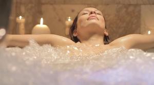 a woman laying in a bath tub with her eyes closed at Hotel SPA Atxaspi in Lesaka