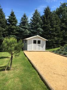 a small white shed with a tree in the yard at Gîte de Roches Hibou in Seigy