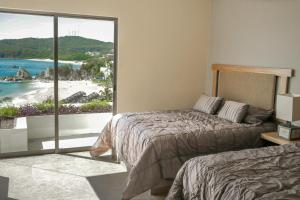 a bedroom with a bed and a view of the beach at 2061 - Lu Iba PH Condo 5 in Santa Cruz Huatulco