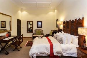 a bedroom with a large bed and a desk at Riverside Guest Lodge in Oudtshoorn